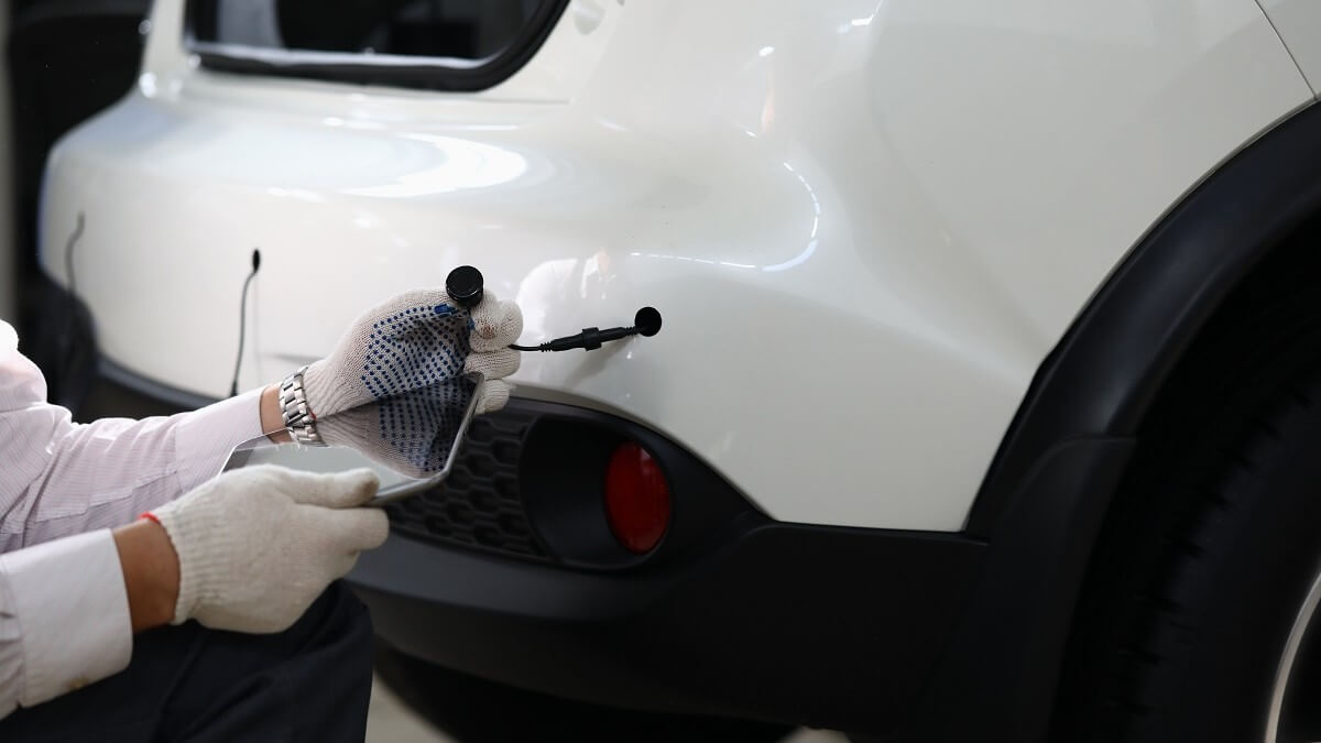 Mechanic installing rear car parking sensor